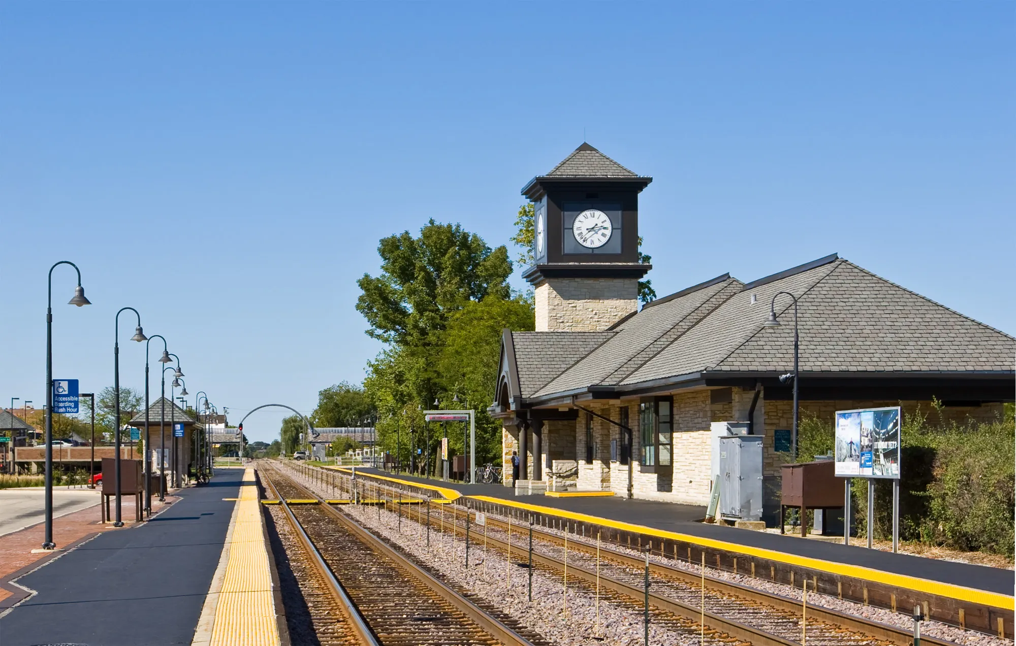 The clock tower and platform of the Highland Park Metra station on a clear autumn day